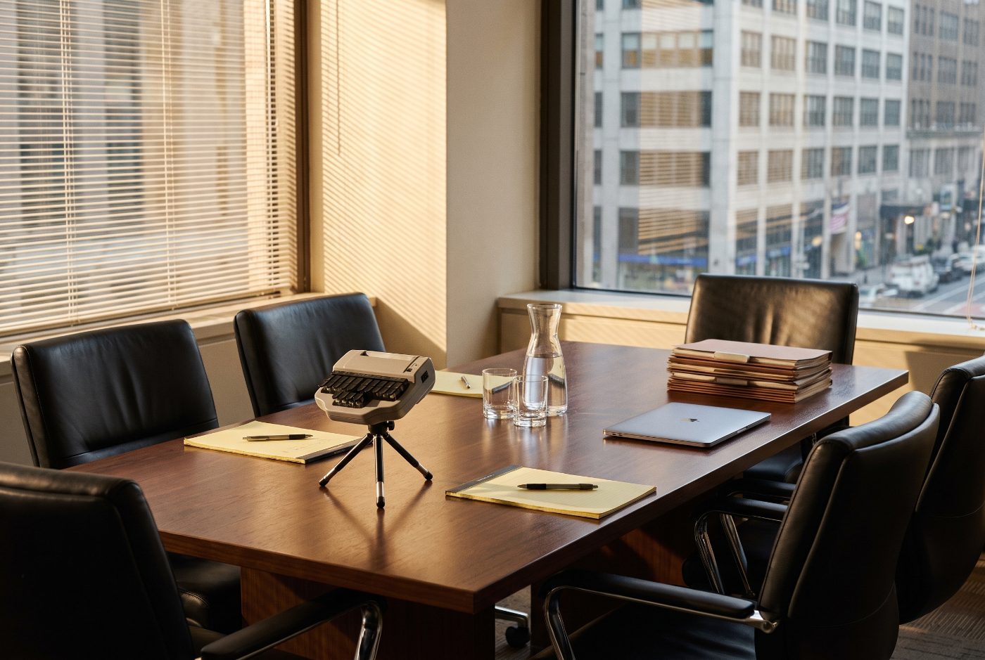 Law office conference room set up for a deposition, with a court reporter’s stenotype machine, legal pads and water glasses on the table